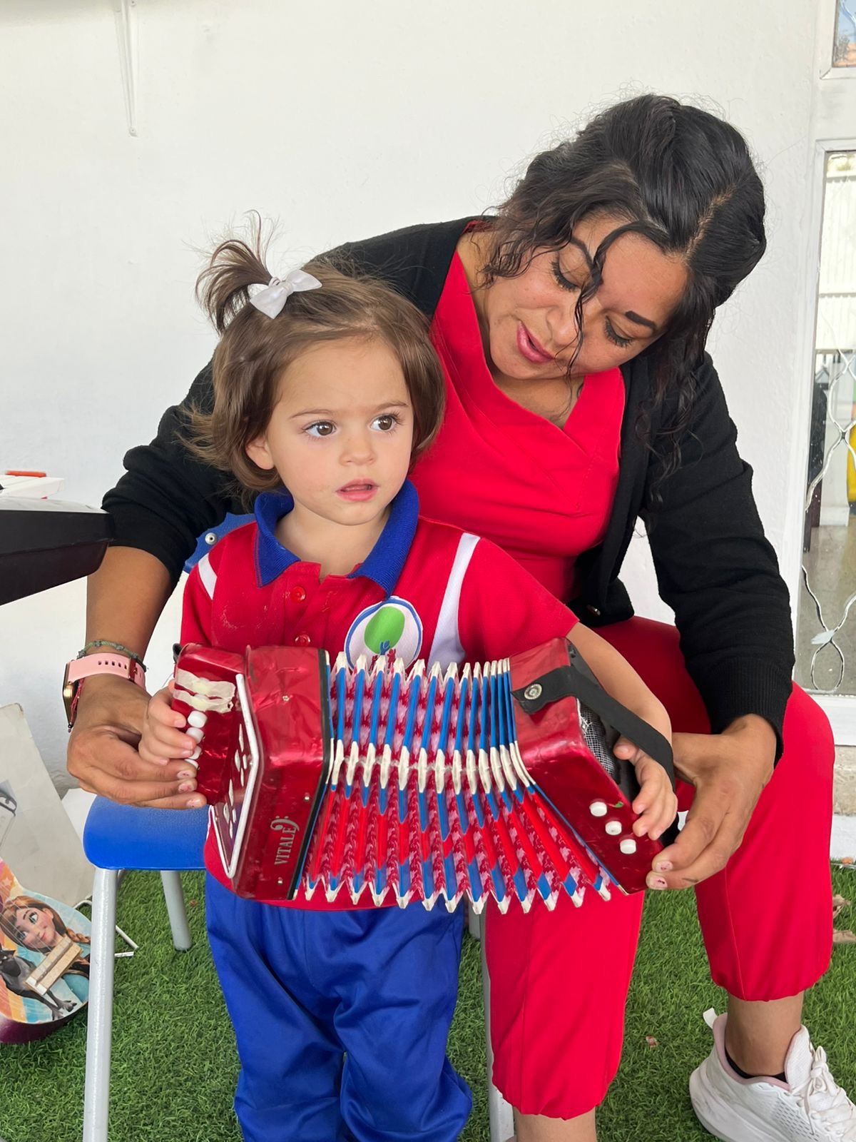 Niña explorando un instrumento musical con su maestra